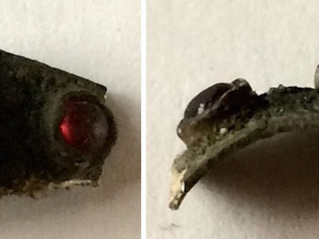 A piece of a silver ring with three red stones
